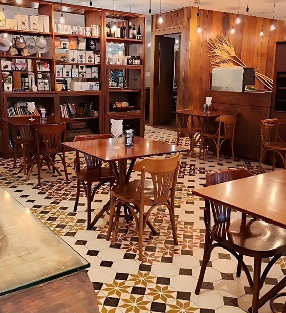 Decoração para cafeteria com mesas quadradas de madeira e iluminação acolhedora