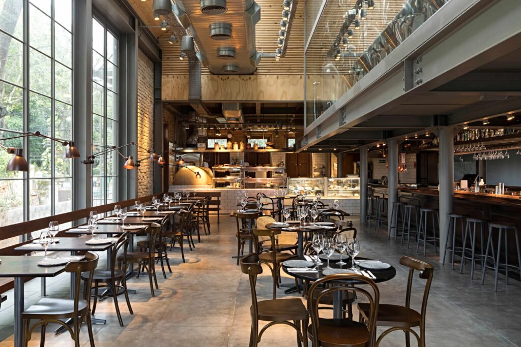Durabilidade de madeiras maciças em restaurante com mesas, cadeiras e salão amplo de estilo industrial