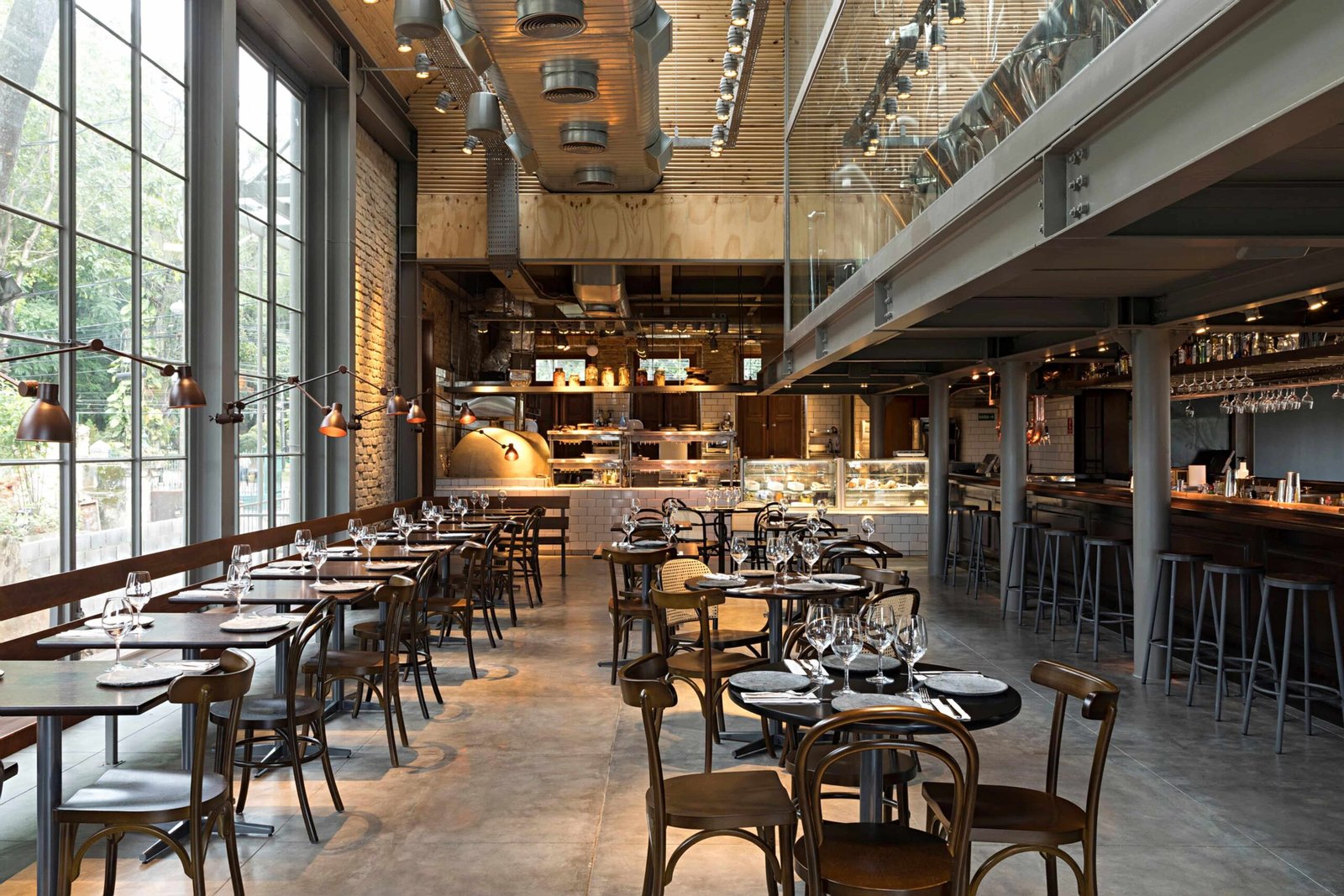 Durabilidade de madeiras maciças em restaurante com mesas, cadeiras e salão amplo de estilo industrial