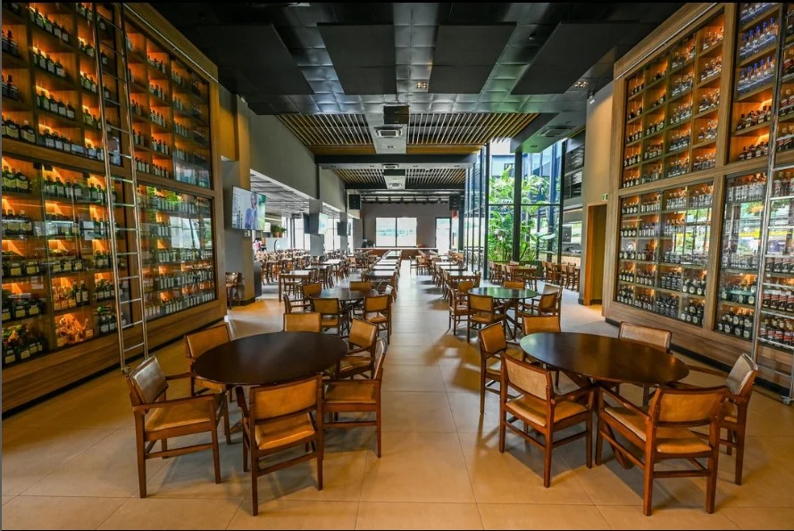 Psicologia do design no Bar do Cuscuz com mesas de madeira, cadeiras e adegas iluminadas