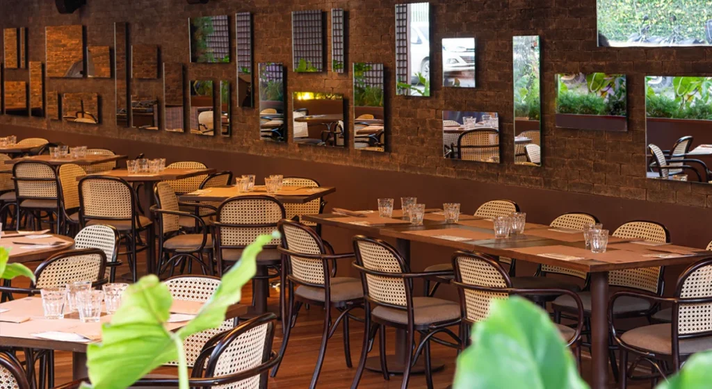 Layout de restaurante da Casa Tua Brasil com mesas de madeira e cadeiras em salão acolhedor